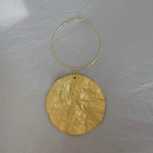 a gold circle pendant on a chain